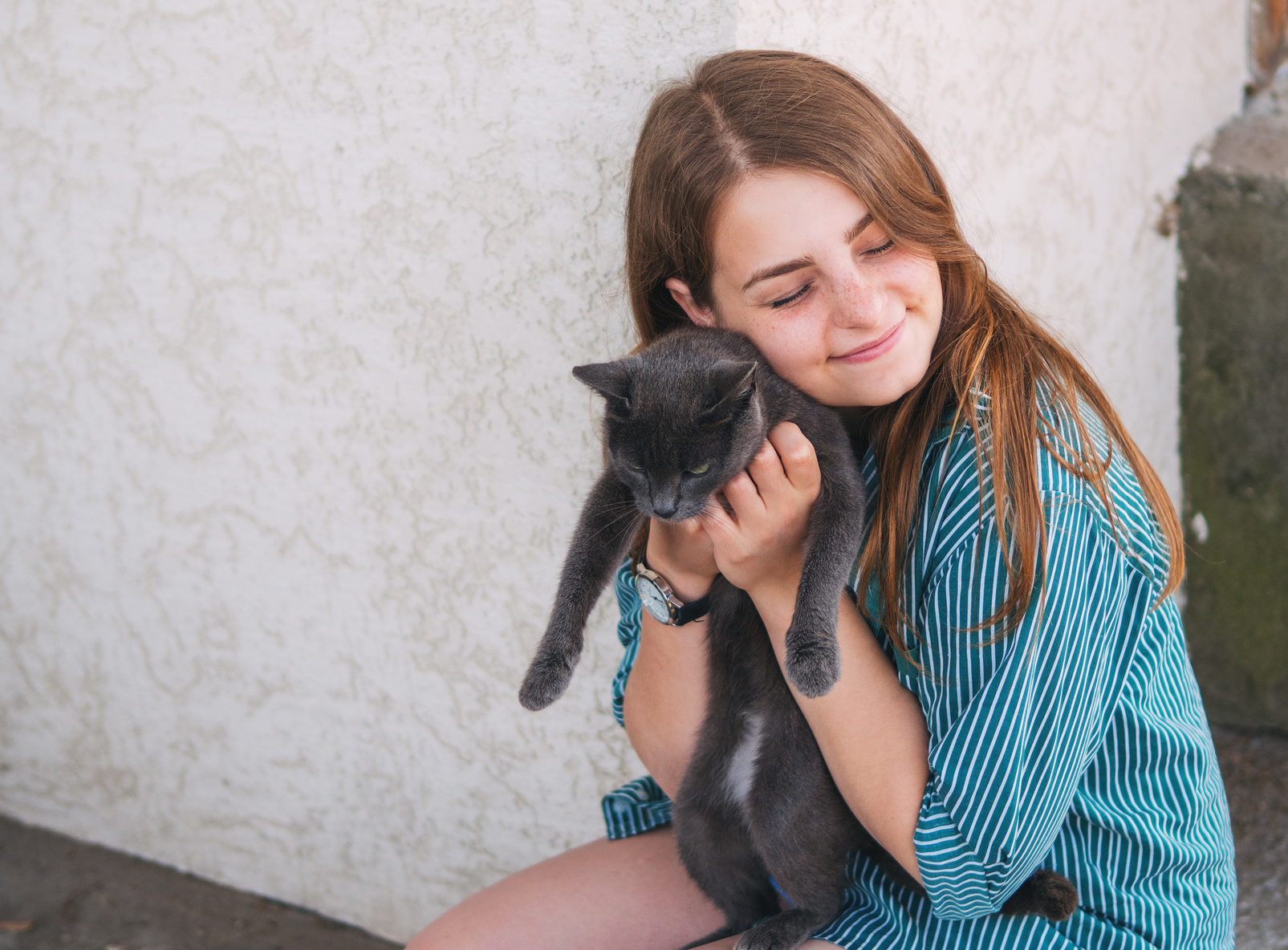 Fotolia_164560557_Subscription_Monthly_M Ein Mädchen knuddelt eine Katze an ihrem Gesicht.